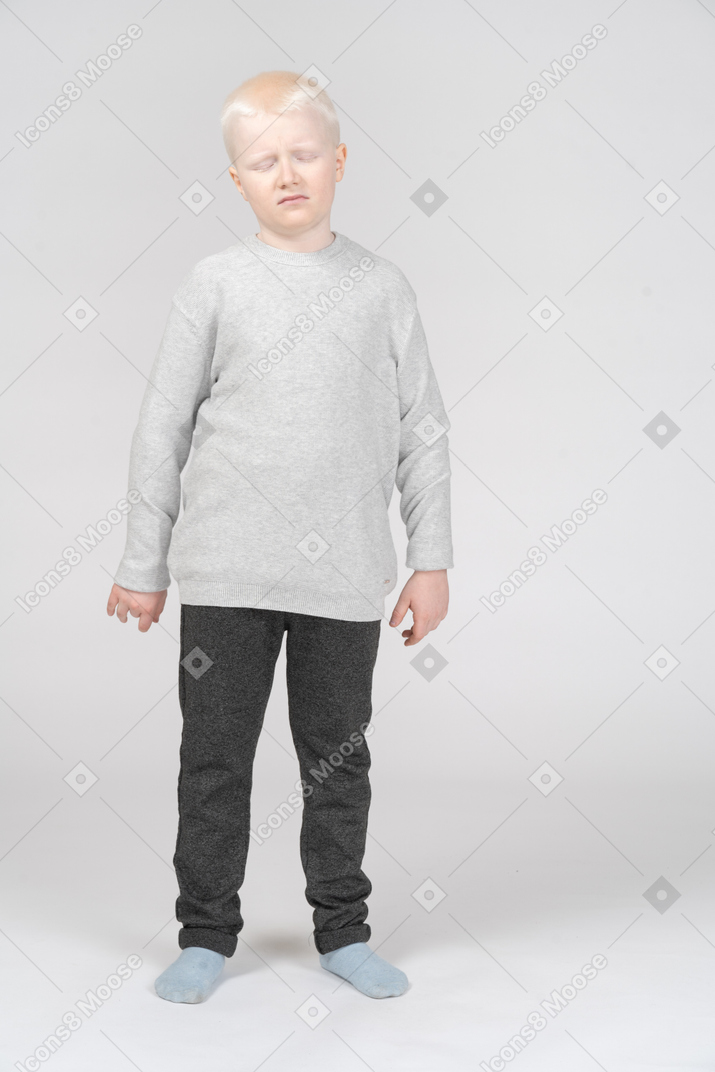Front view of a blonde little boy in a bad mood