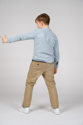 Boy standing back to camera and pointing to something