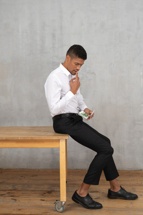 Homme bien habillé comptant de l'argent assis sur une table