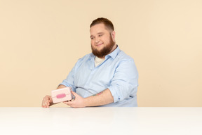 Grande homem sentado à mesa e segurando a lancheira