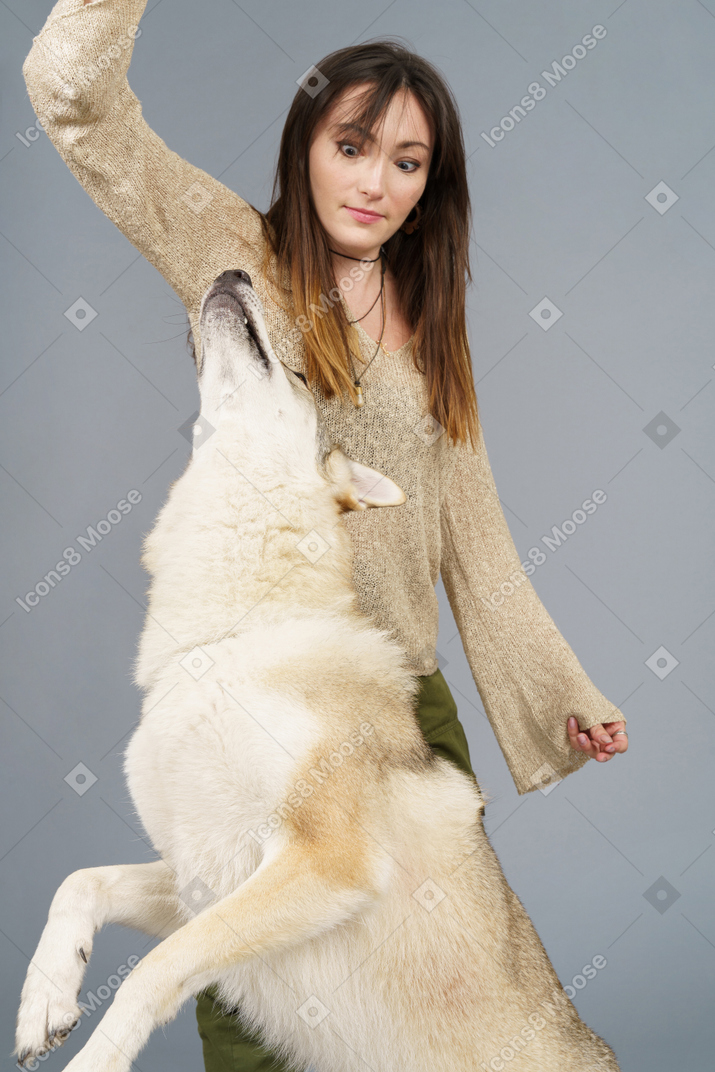 Close-up of a surprised female raising hand and looking surprisingly at her jumping dog