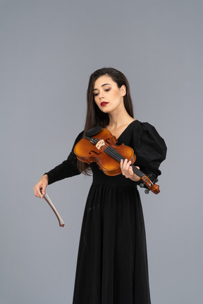 Close-up de uma jovem de vestido preto tocando violino