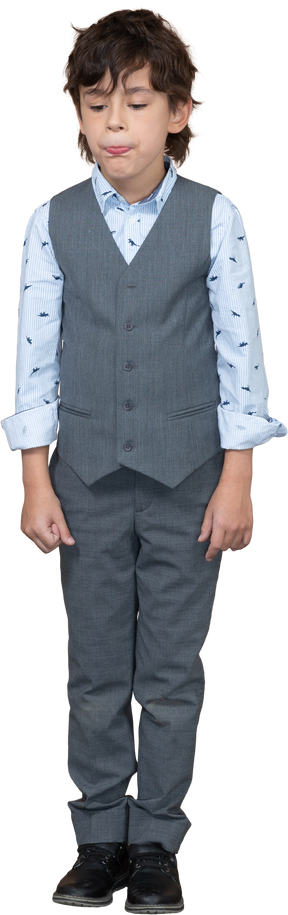 Vista frontal de um menino fofo em um terno cinza fazendo caretas