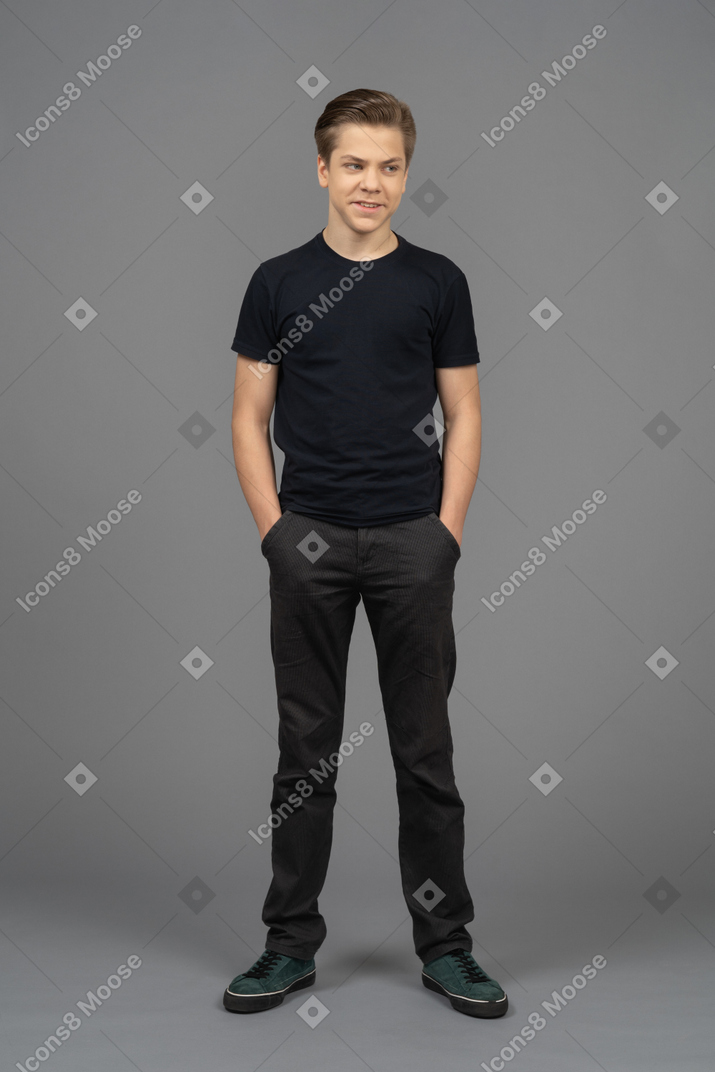 A cheerful young man standing with his hands in pockets