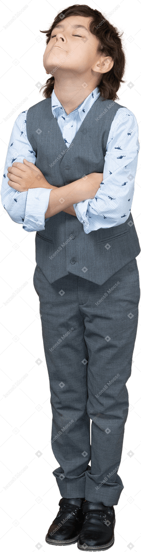 Vista frontal de um menino de terno posando com braços cruzados