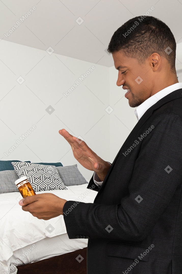 Man in a suit looking with disgust at a bottle of pills