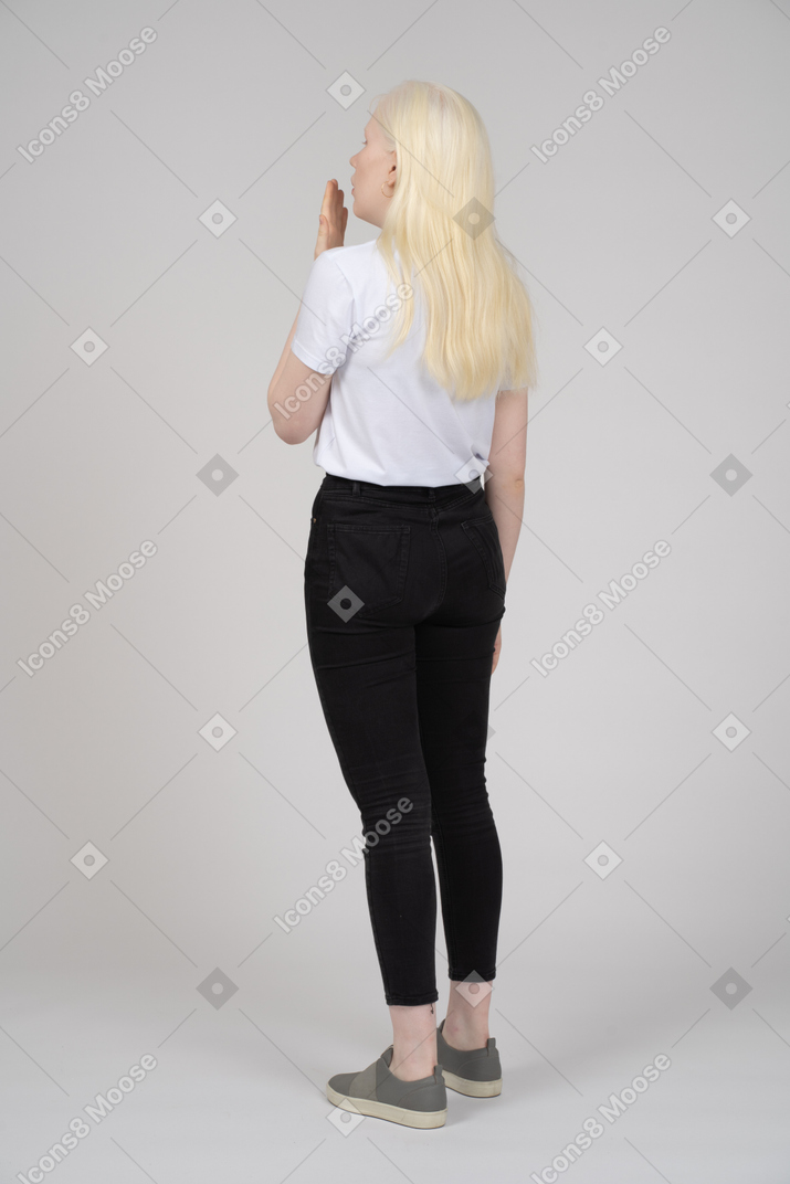 Vista posteriore di tre quarti di una giovane donna che sbadiglia e copre la bocca con la mano