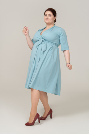 一个快乐的女人在蓝色连衣裙摆姿势的前视图