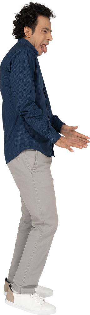 Vista lateral de um homem com roupas casuais mostrando a língua e gesticulando