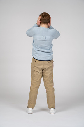 Back view of a boy covering ears with hands