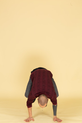 Front view of a young man in red pullover leaning on his arms