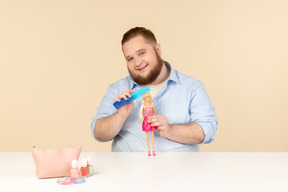 Großer mann, der haarbürste und barbie-puppe hält