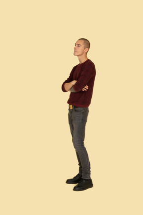 Three-quarter view of an offended young man dressed in casual clothes crossing his hands