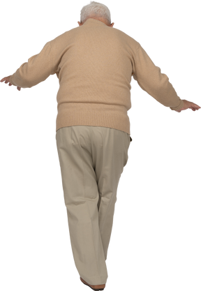 Vista posteriore di un vecchio in abiti casual che cammina con le braccia tese