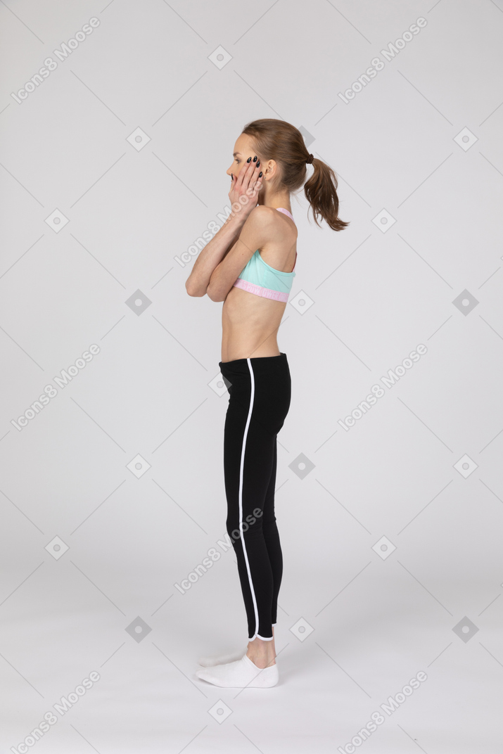 Side view of a teen girl in sportswear hiding her mouth