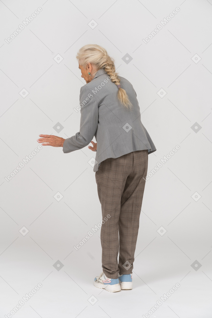 Rear view of an old lady in suit bending down