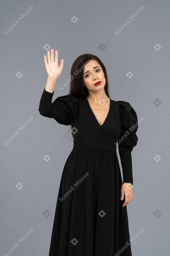 Вид спереди грустно приветствующей молодой леди в черном платье