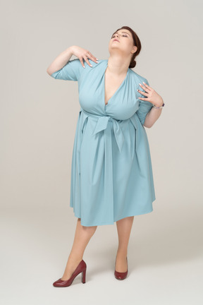 Vista frontale di una donna in abito blu in posa con le mani sulle spalle