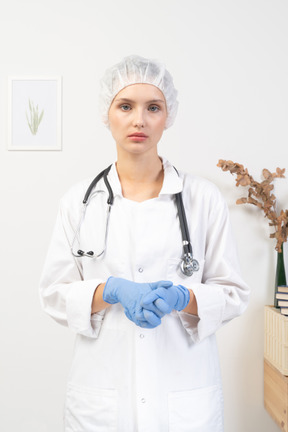 Vista frontal de uma jovem médica cansada com estetoscópio de mãos dadas