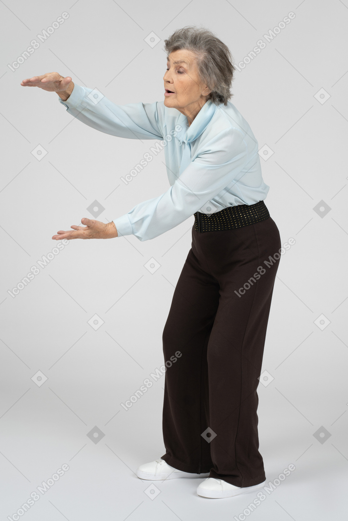 Пожилая женщина показывает размер обеими руками
