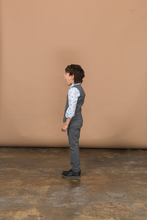 Vista lateral de um menino de terno em pé com a boca aberta