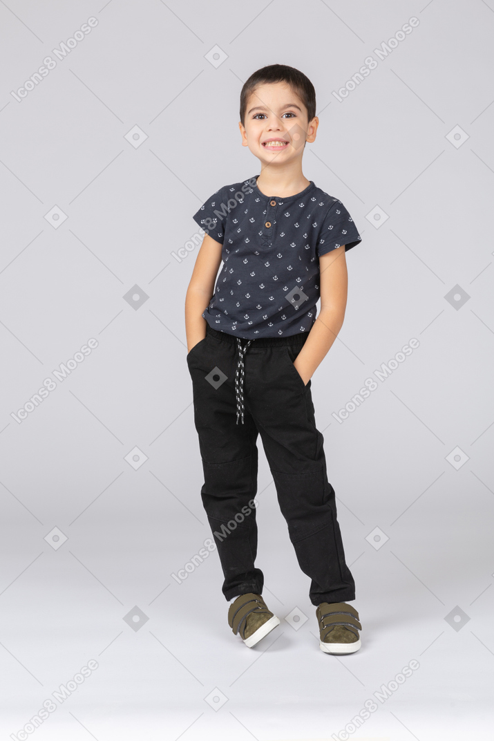 Vista frontale di un ragazzo felice in posa con le mani in tasca