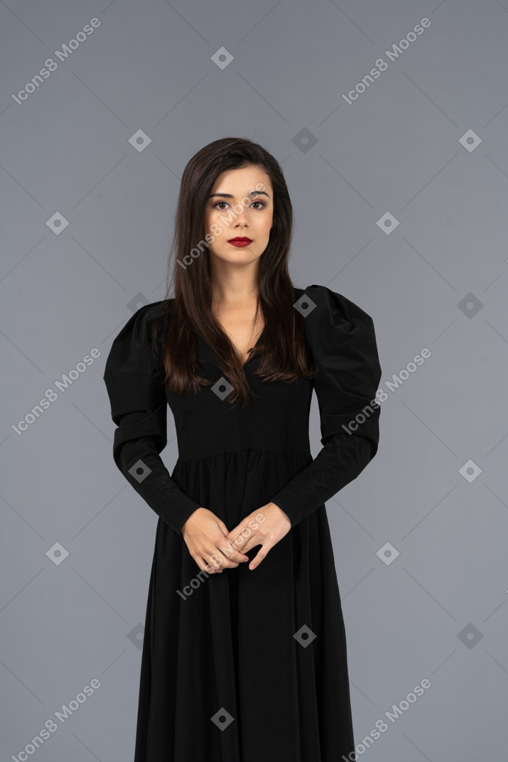 静止している黒いドレスを着た若い女性の正面図