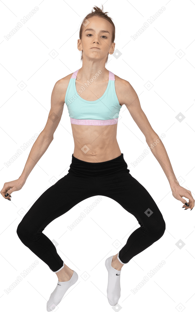Vista frontal de uma adolescente em roupas esportivas pulando