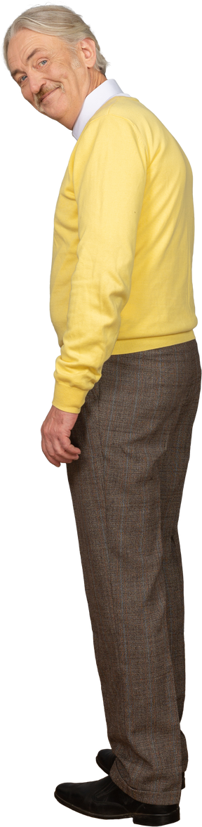 Vista posteriore di tre quarti di un uomo anziano che indossa un pullover giallo e sorride mentre guarda la fotocamera