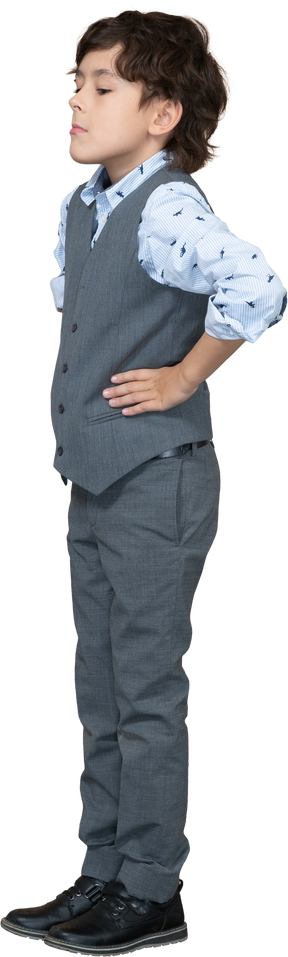 Vista laterale di un ragazzo in giacca e cravatta in posa con le mani sui fianchi