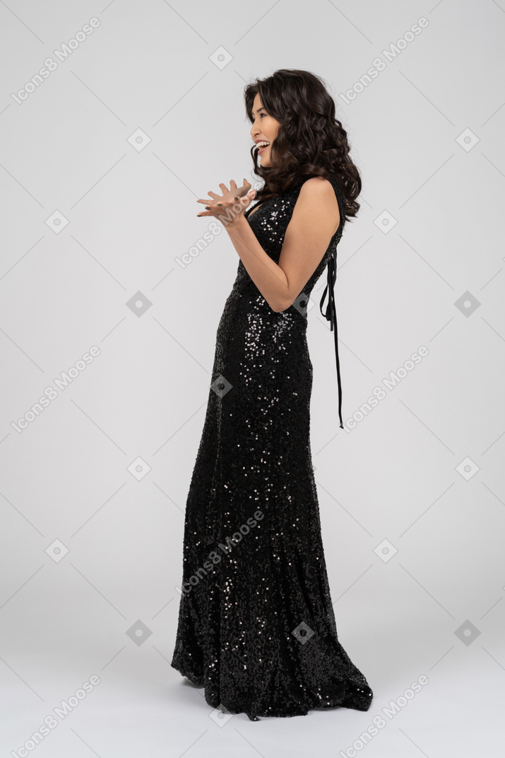 검은 이브닝 드레스를 입고 여자는 기뻐 보인다