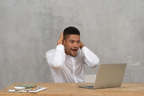 Young man looking at screen and touching his neck