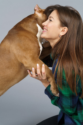 Side view of a smiling female in checked shirt hugging her bulldog