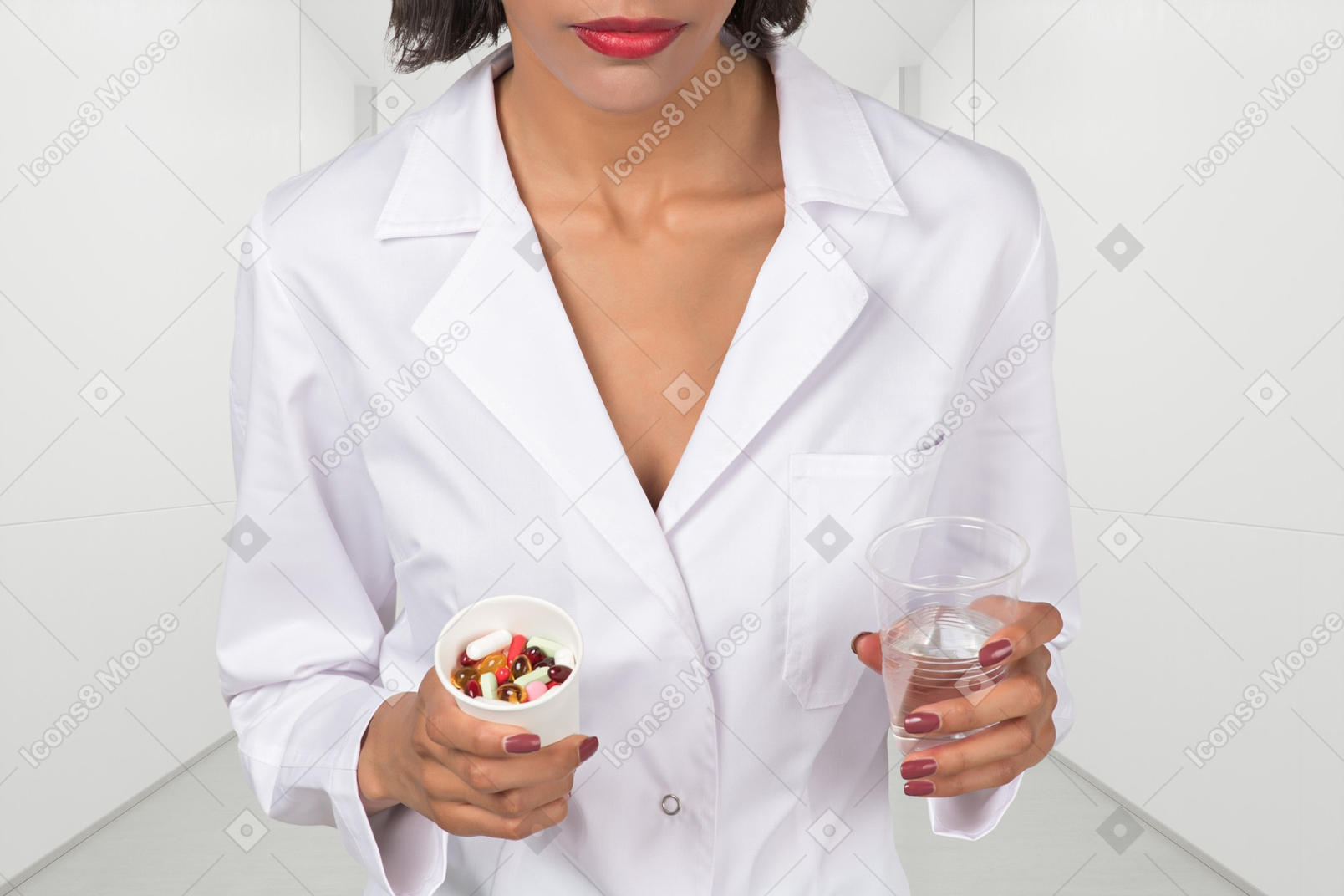 A woman in a white lab coat holding pills and cup of water