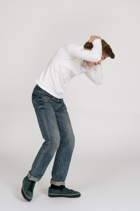 A man in white shirt and jeans holding his head