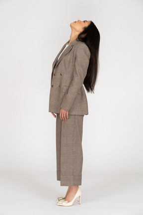 頭を後ろに投げる茶色のビジネススーツの若い女性の側面図