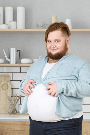 A man showing of his belly in a kitchen