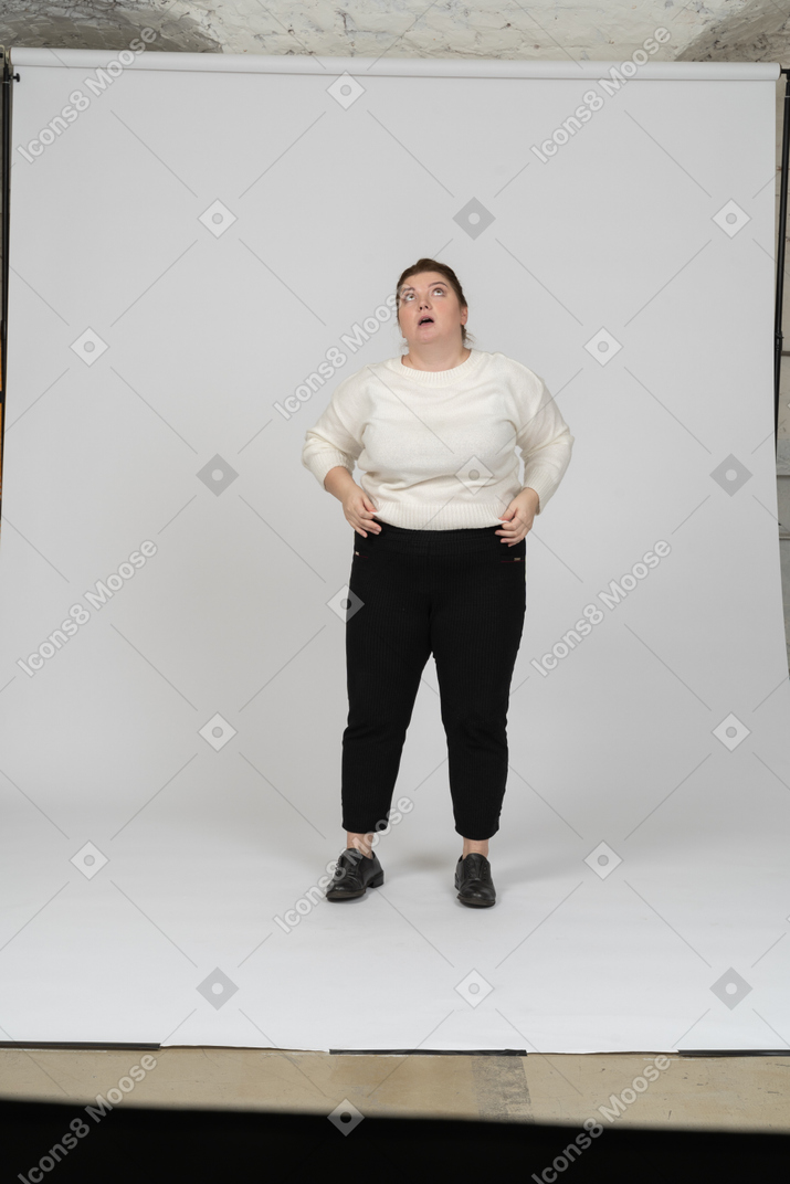 Impressed plump woman in casual clothes looking up