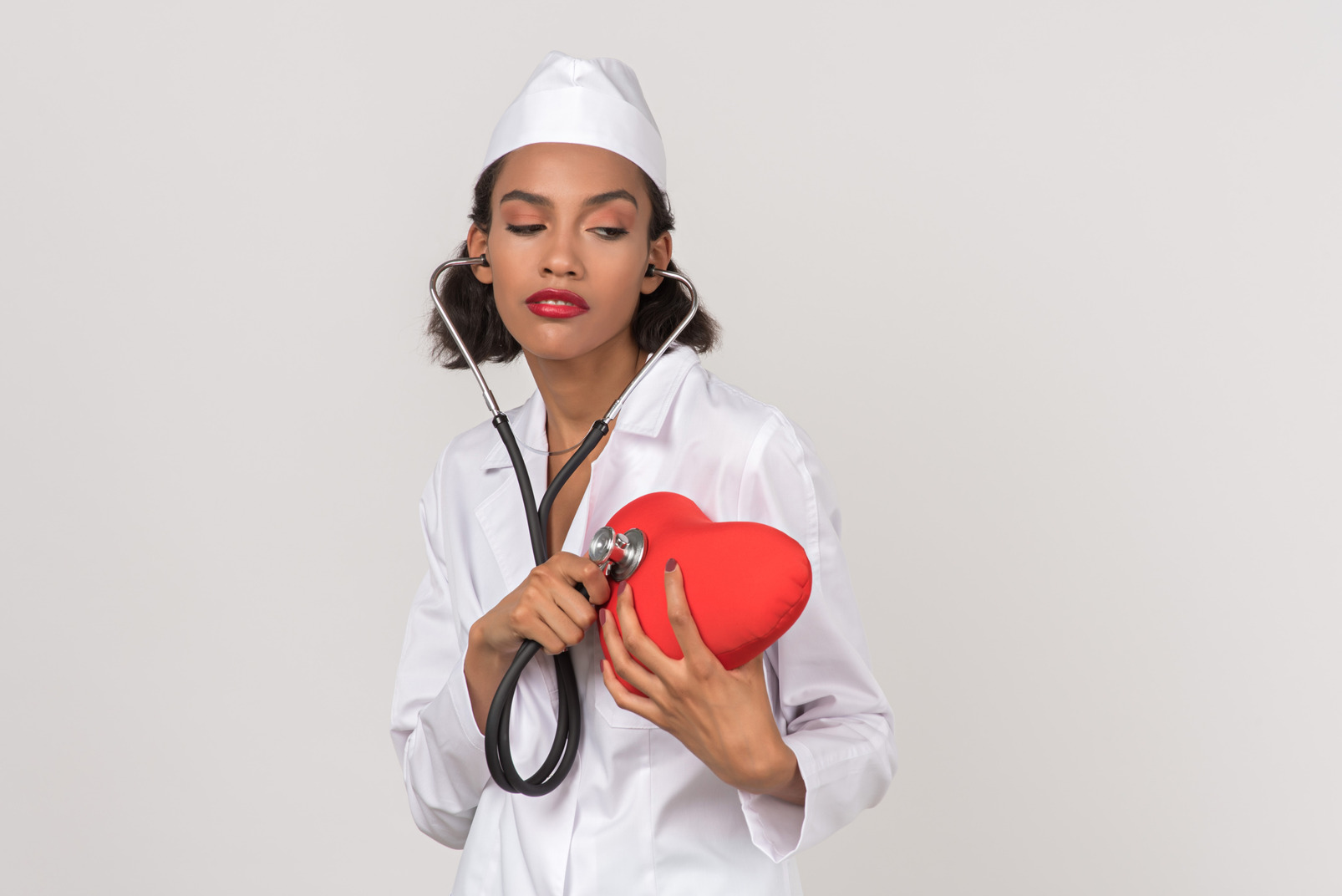 Attractive female doctor making auscultation of a toy heart