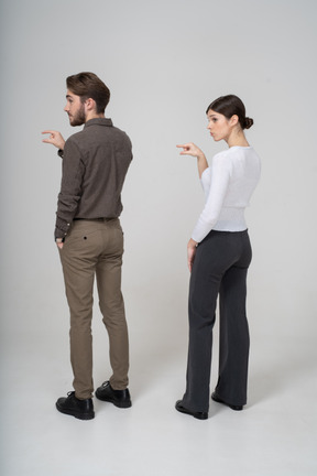 Vista posteriore di tre quarti di una giovane coppia in abiti da ufficio che mostra le dimensioni di qualcosa