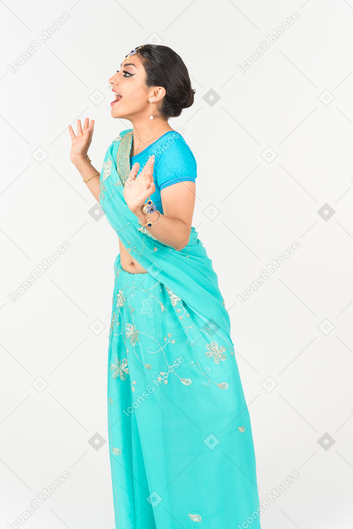 Excited young indian dancer in blue sari standing half sideways