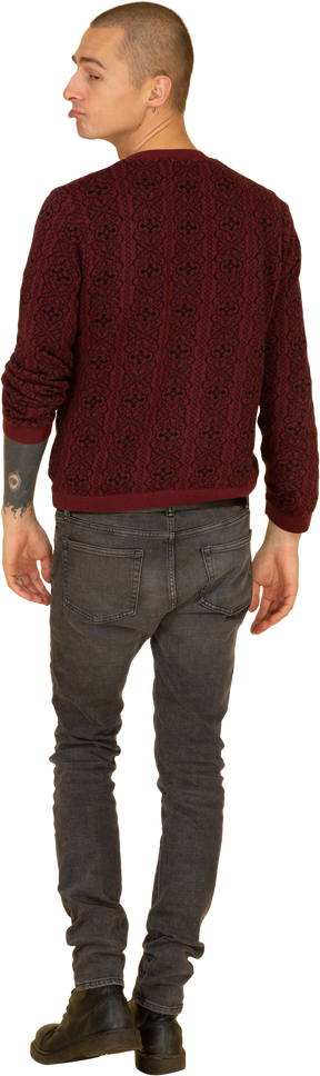 Вид сзади на гримасничающего молодого человека в красном пуловере, смотрящего в сторону