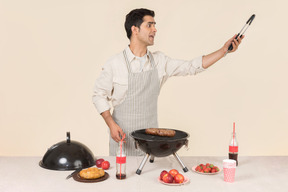 Joven hombre caucásico gritando algo mientras prepara barbacoa