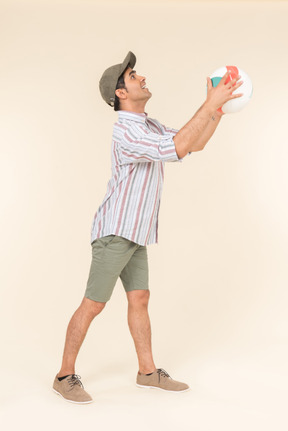 Young caucasian guy standing in profile and holding ball