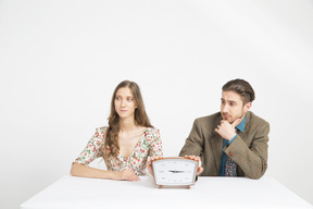 Couple assis à la table et tenant une horloge