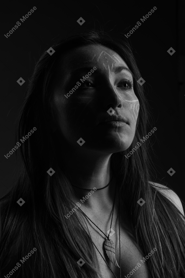 Голова к плечу нуар портрет обнадеживающей молодой женщины с фейс-артом, смотрящей в сторону