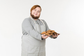 A smiling fat man offering to try homemade cookies