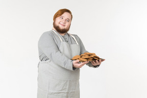 Um homem gordo sorridente oferecendo para experimentar biscoitos caseiros