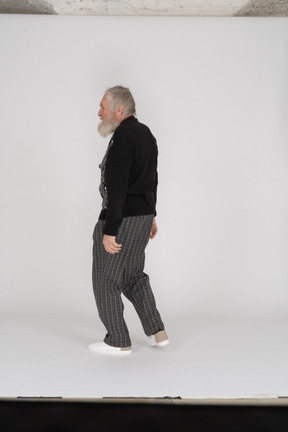 Vue latérale d'un homme âgé marchant avec les bras sur les côtés