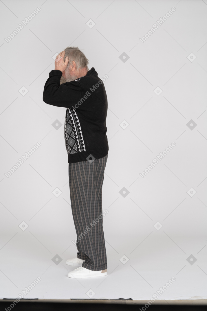 Side view of old man with hands on head